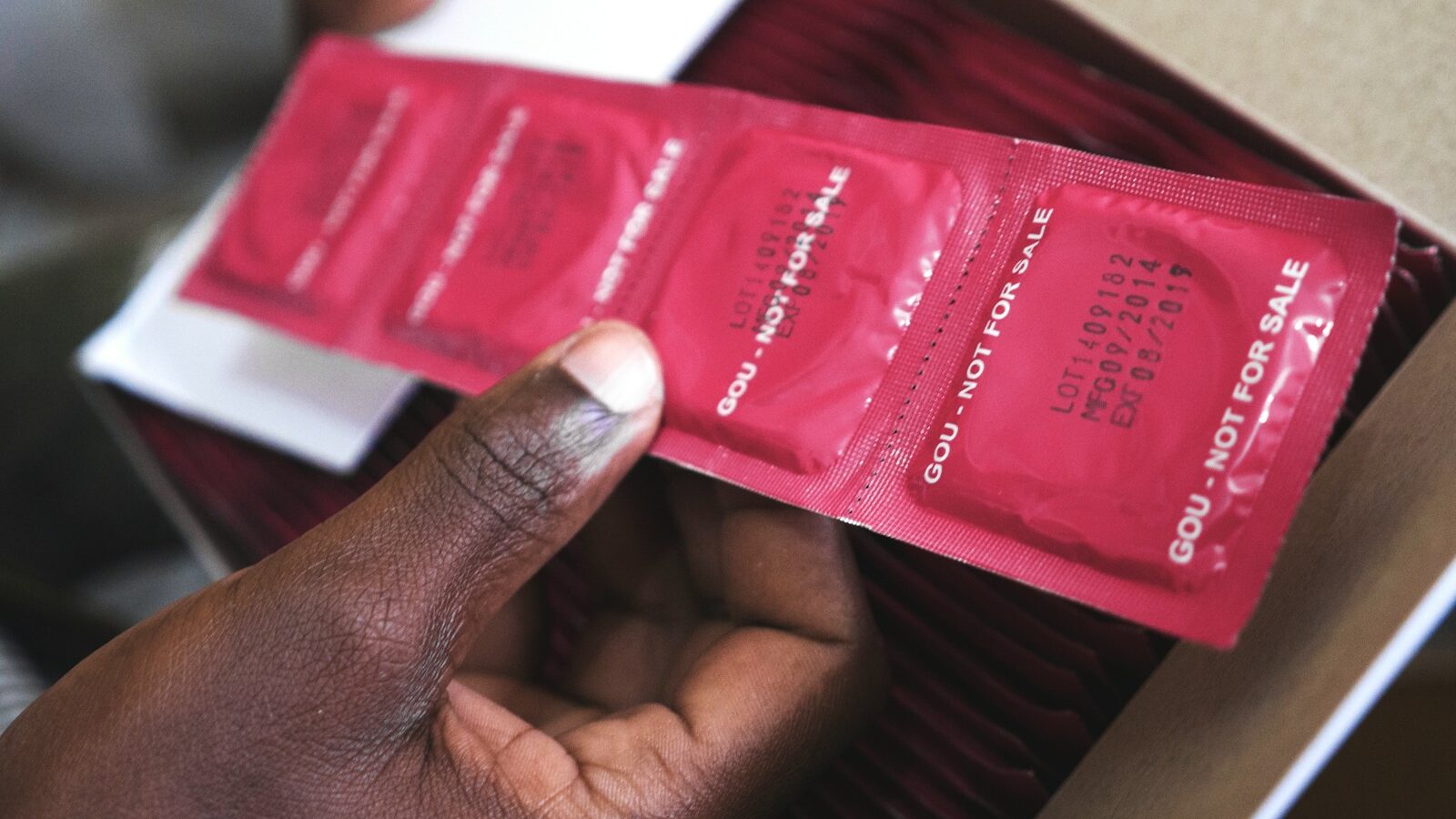 man holding red condom packs